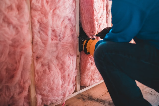 Worker installing pink insulation.