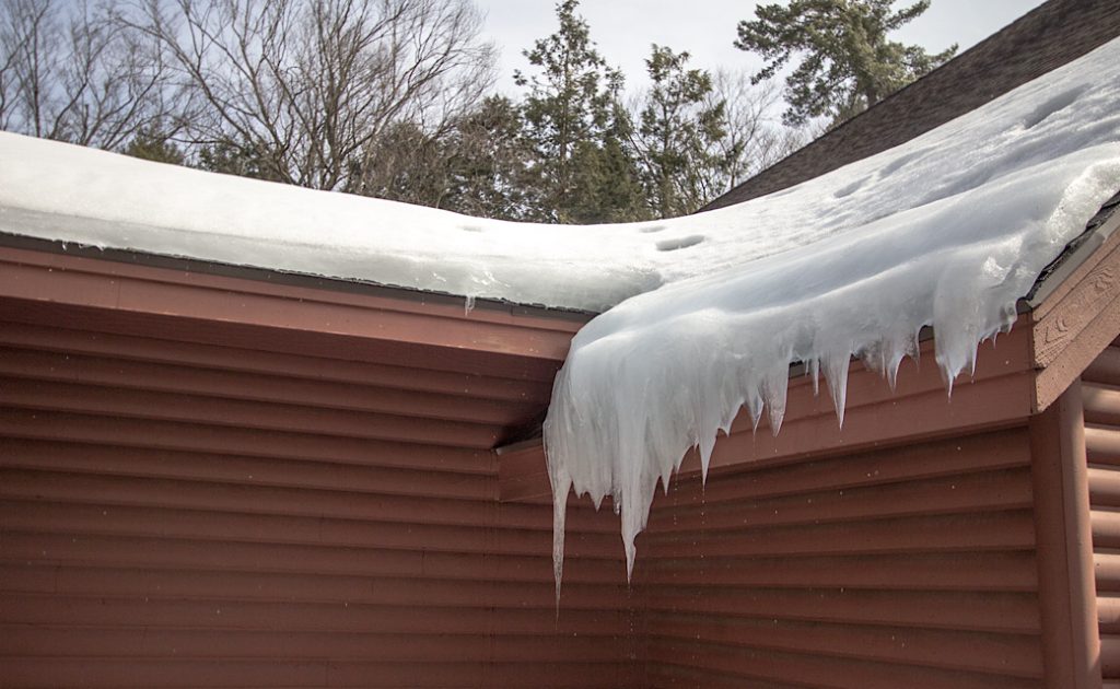snow and ice hanging off residential roof
