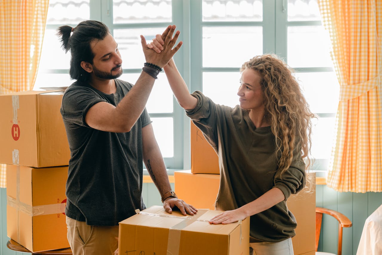 A couple high-fiving next to a cardboard box